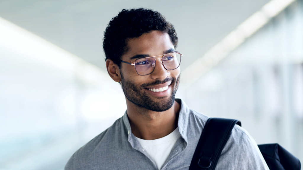 Egy hátizsákot és ZEISS Digital SmartLife szemüveglencsét viselő fiatal mosolygó férfi, aki oldalra néz.